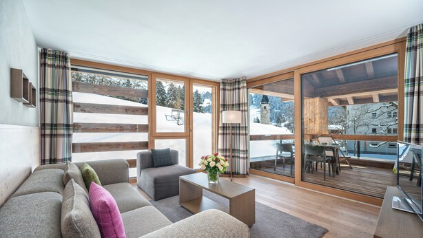 En moderne stue med sofa, sofabord og udsigt til et sneklædt område.