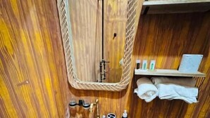 A bathroom with a wooden vanity, a large ceramic sink, a toilet, and a mirror.