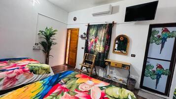Un dormitorio con dos camas, un televisor, un espejo y una puerta.