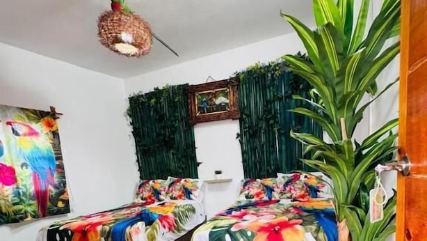 A room with two beds, a wooden floor, a hanging light fixture, and a door.
