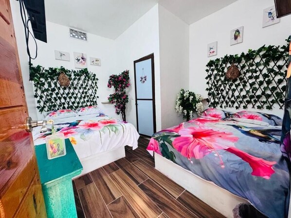 A bedroom with two beds, a wooden cabinet, and a TV.