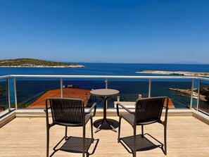 A balcony with two chairs and a small table, overlooking a clear blue sea and a distant island. - Miromara Hotel Karaburun (Karaburun)