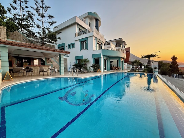A modern hotel with a swimming pool, outdoor seating, and a bar area. - Miromara Hotel Karaburun (Karaburun)