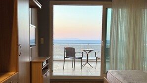 A room with a bed, a small table, and a chair facing a balcony with a view of the sea. - Miromara Hotel Karaburun (Karaburun)