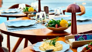 A seaside dining area with tables set for meals, overlooking the ocean. - Miromara Hotel Karaburun (Karaburun)