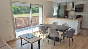 Una cocina moderna con una isla central, una zona de comedor con mesa y sillas, y un puerta corrediza de vidrio que da a un patio exterior.