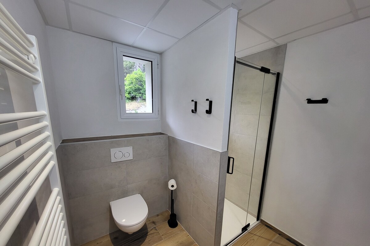 Un baño moderno con inodoro, ventana y zona de ducha.