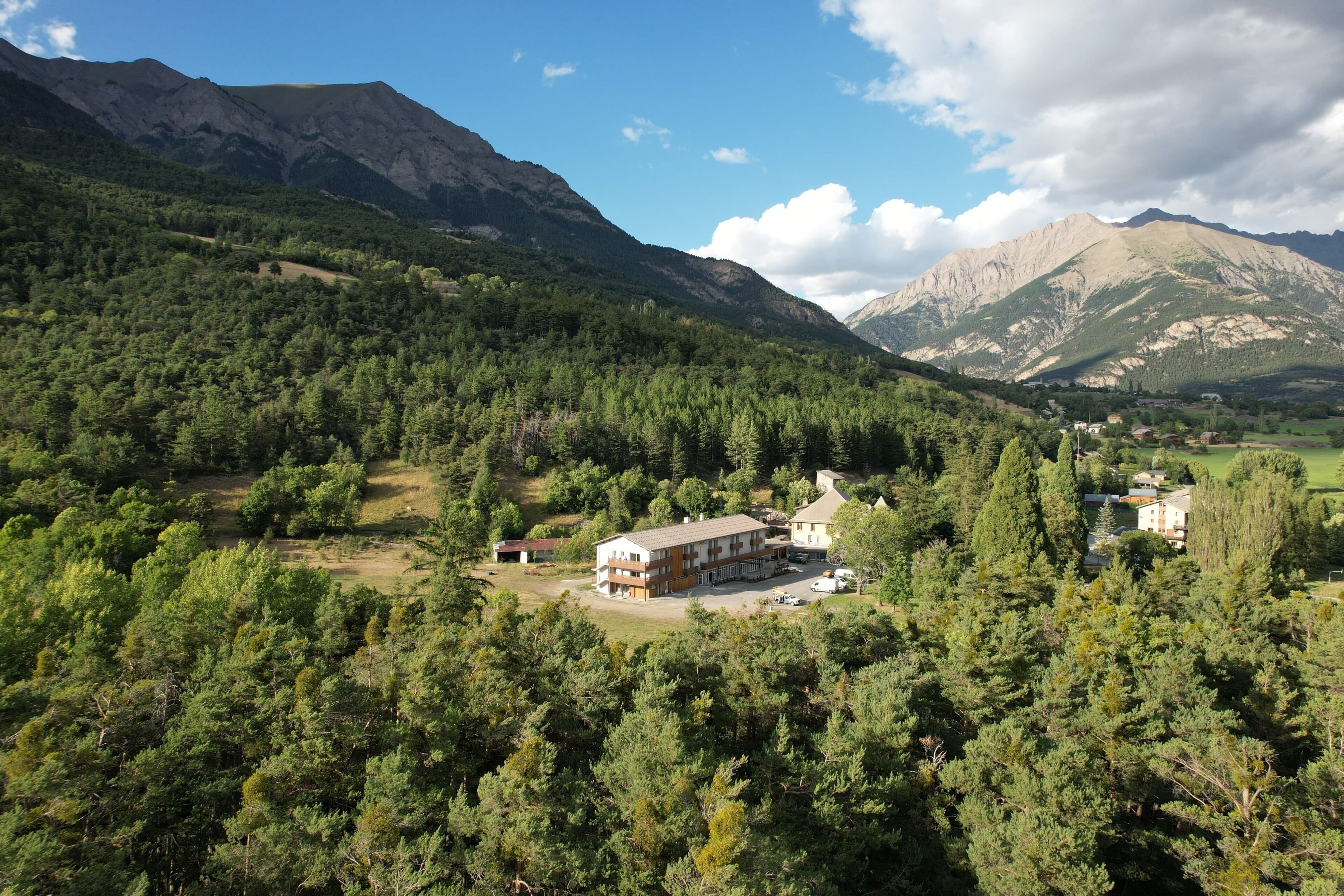 A mountain lodge with a modern design, surrounded by dense forest and mountains.