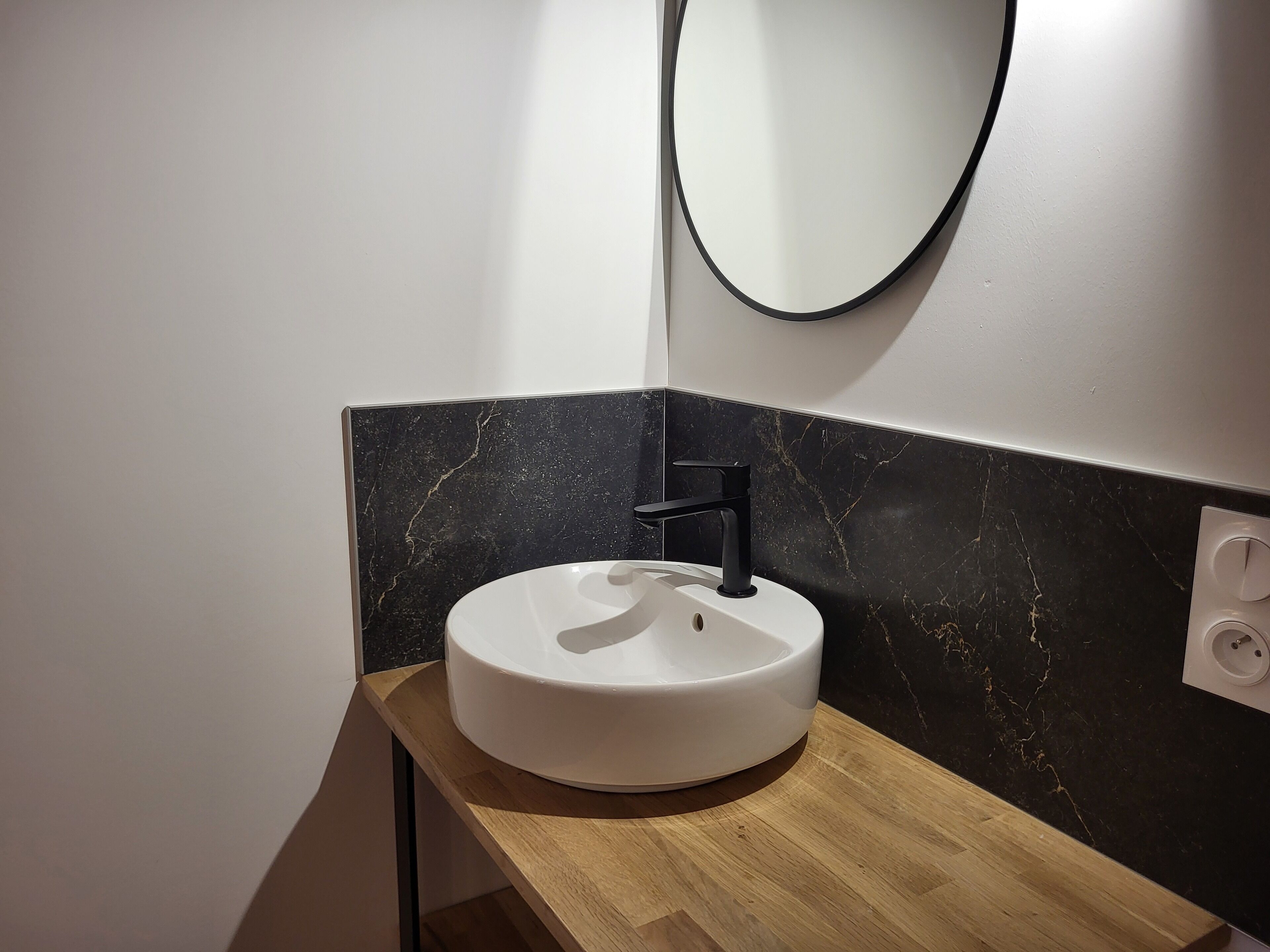 A bathroom with a white sink, black faucet, and a mirror.