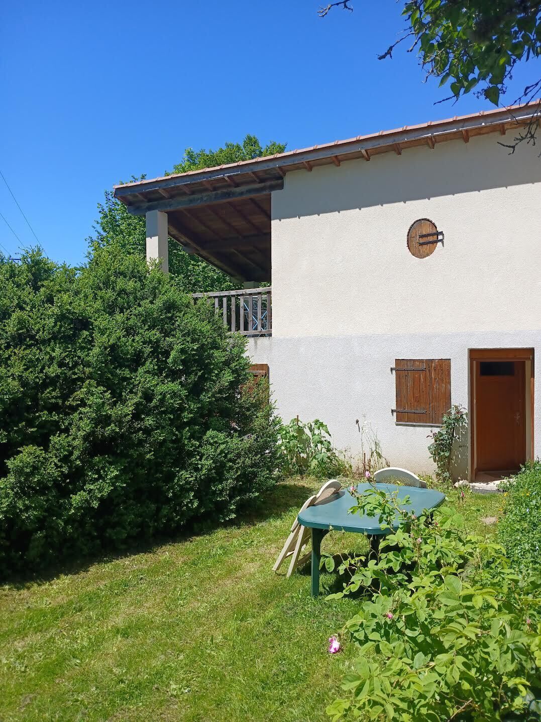 Uma casa de dois andares com uma varanda, rodeada por vegetação exuberante.
