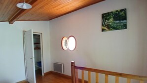 A room with wooden flooring, a staircase with a wooden railing, a white door leading to a closet, and a wall-mounted mirror.