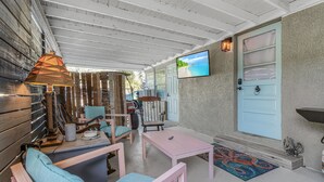 Un patio couvert avec des murs en bois, un téléviseur fixé au mur et un luminaire.