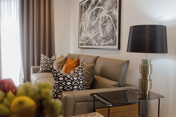 Un soggiorno con un divano, cuscini decorati, una lampada moderna e un quadro astratto incorniciato al muro.