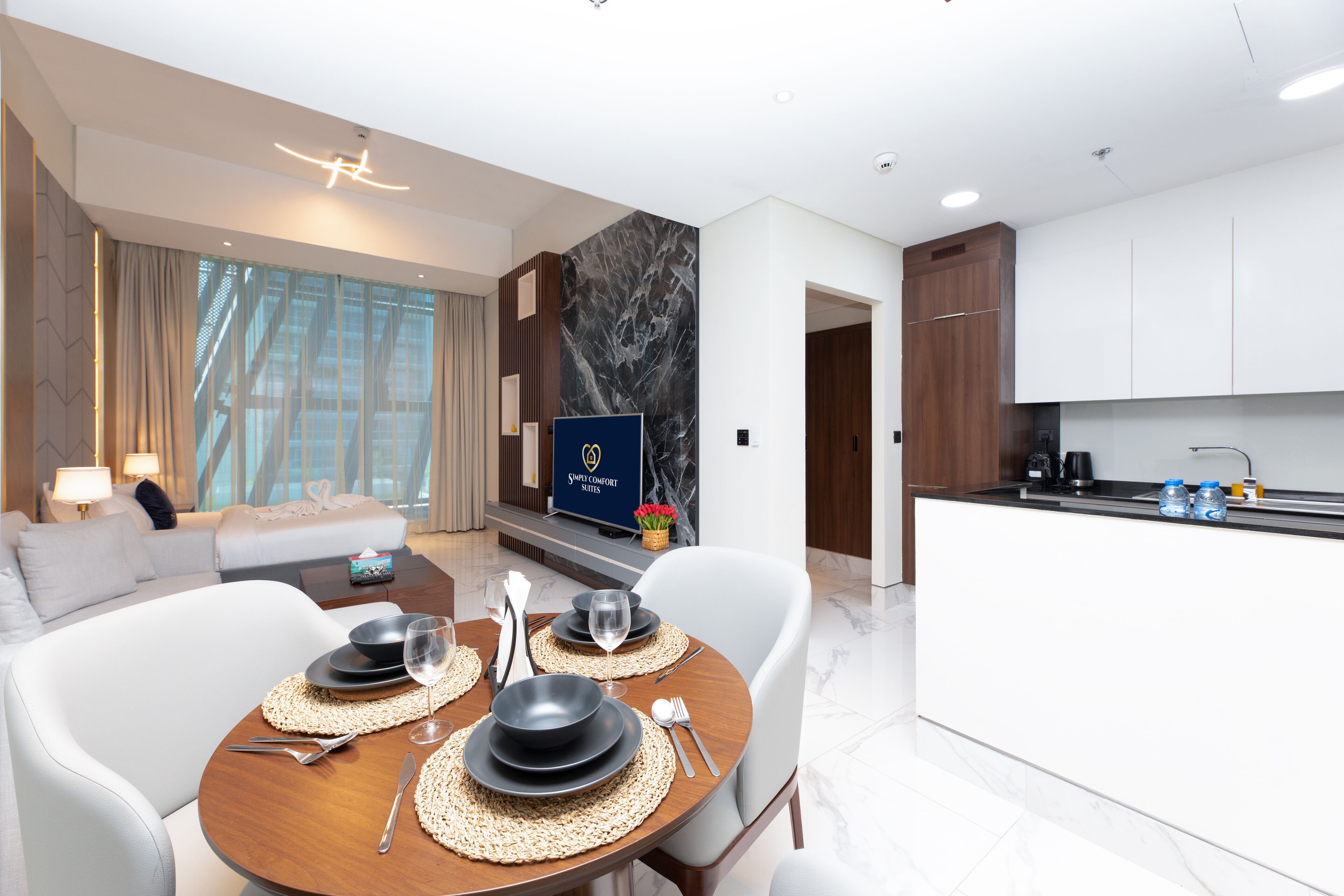 A modern hotel room with a dining area, a living room, and a kitchen.