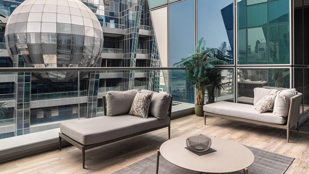 A modern lounge area with a sofa and a coffee table, large windows offering views of a cityscape and a unique spherical structure. - SIMPLY COMFORT Urban Chic Suites in J One Tower City & Canal Views (Dubai)