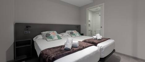A modern hotel room with two beds, a large mirror, and a small bedside table.