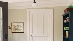 A room with a white door, a beige armchair, a floor lamp, and a dark blue bookshelf. - Amazing 3-bedroom cottage. 5 Min-walk to beach. Beach side of Oak Island Drive (Oak Island)