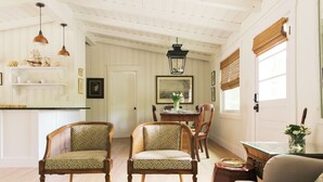 A well-lit room with a dining table, chairs, and a sofa. - Amazing 3-bedroom cottage. 5 Min-walk to beach. Beach side of Oak Island Drive (Oak Island)