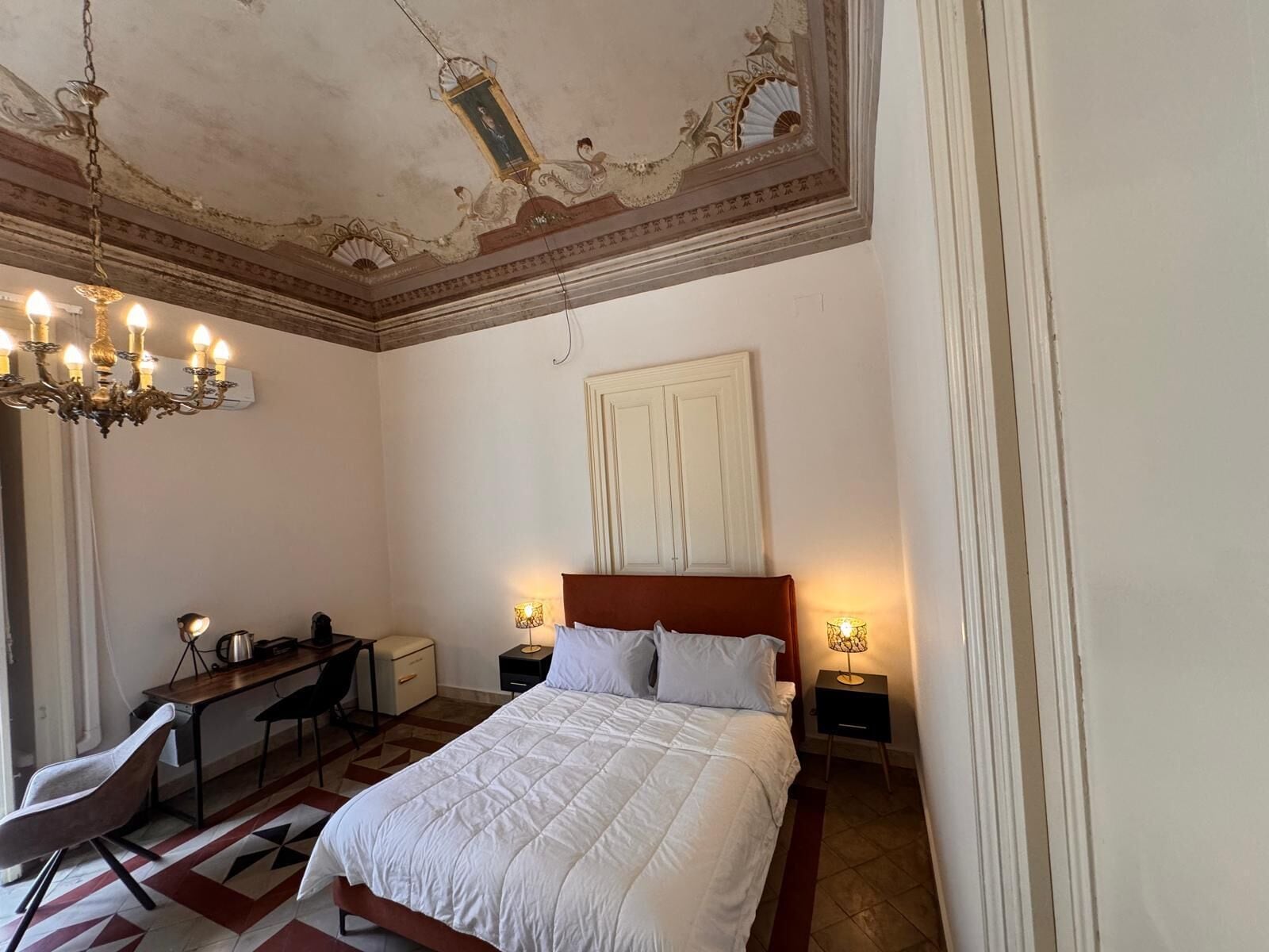 A bedroom with a large bed, a desk, and two bedside tables with lamps.