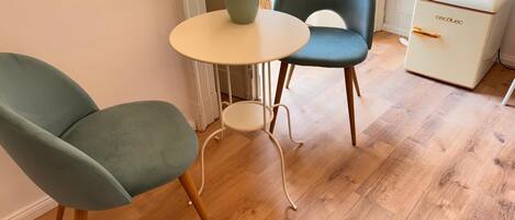 Une pièce comprenant deux fauteuils de couleur turquoise, une petite table ronde et un meuble blanc.