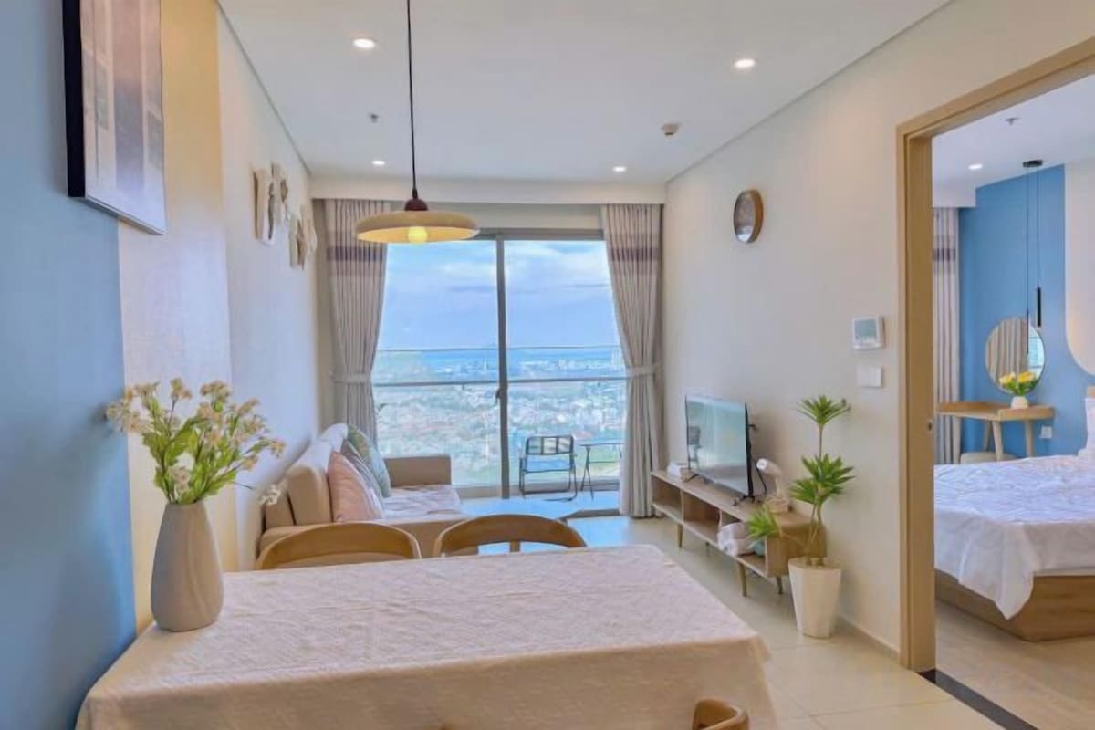 A hotel room with a balcony, a dining area, and a TV.