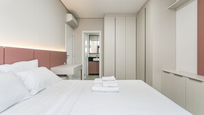 Una habitación de hotel con una cama bien hecha, una mesita de noche y vistas al baño.