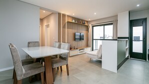 Una cocina moderna con comedor, estantes empotrados, televisor y un amplio ventanal.
