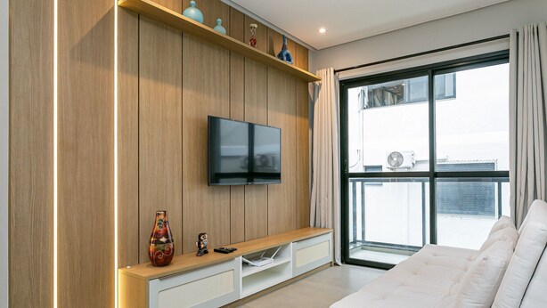 Una sala de estar moderna con una pared de madera, un televisor de pantalla plana, un sofá y una ventana con vistas a la ciudad.