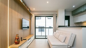 Una sala de estar moderna con un sofá, un televisor instalado en la pared y un mueble de madera.