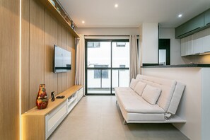 Ein modernes Wohnzimmer mit einer Couch, einem an der Wand montierten Fernseher und einem Holzschrank.