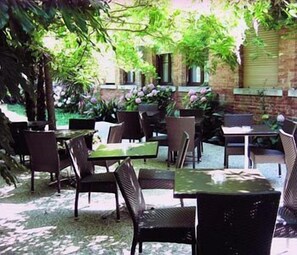 Une terrasse extérieure avec des meubles en osier et des murs en briques.