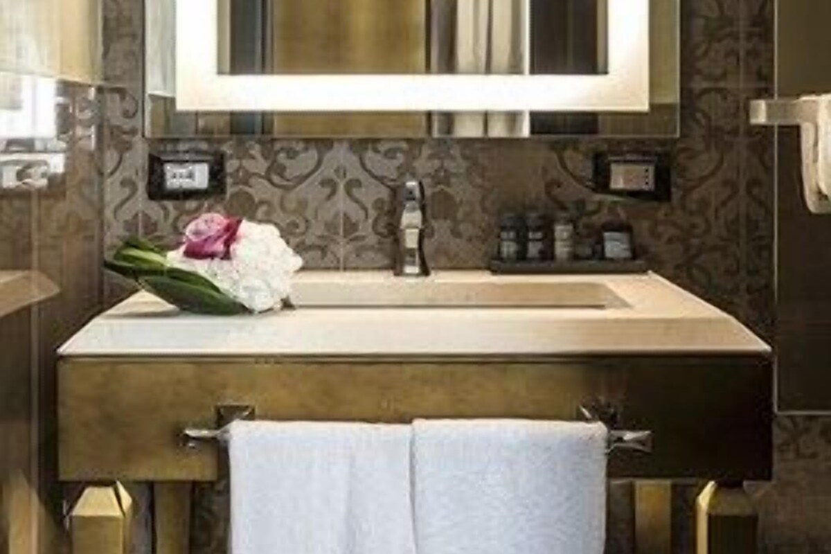 A bathroom with a large mirror, a sink, and a towel rack.