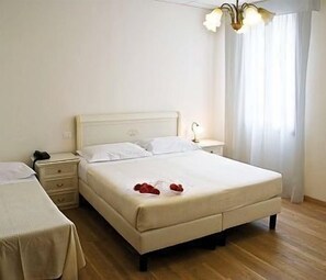 A hotel room with a double bed, bedside tables, a lamp, and a chandelier. - The Venice Times (Venice)