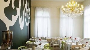 A restaurant with tables set for dining, a chandelier, and a large abstract wall art piece. - The Venice Times (Venice)