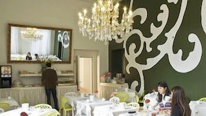 A dining area with tables set for guests, a chandelier, and a large mirror on the wall. - The Venice Times (Venice)