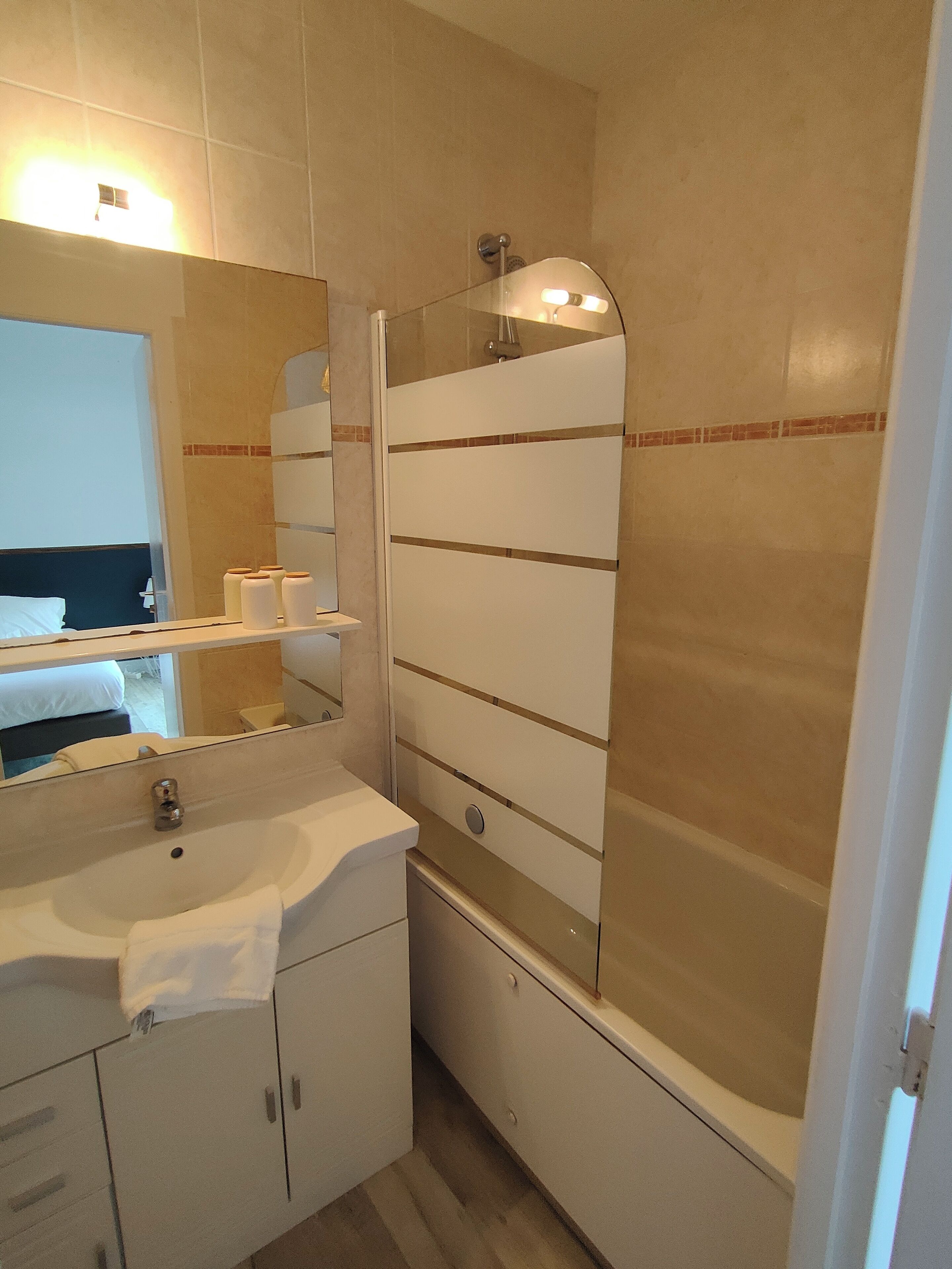 A bathroom with a sink, mirror, and shower.