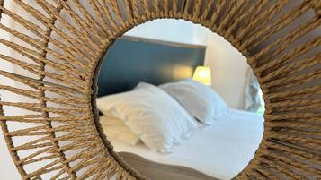 Un miroir rond tressé qui reflète une image d’un lit et d’une lampe.
