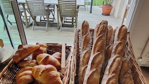 Una mesa de madera con cestas de pan y vistas a un patio al aire libre con sillas y mesas.
