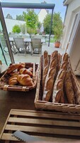 A wooden table with baskets of bread and a view of an outdoor patio area with chairs and tables.