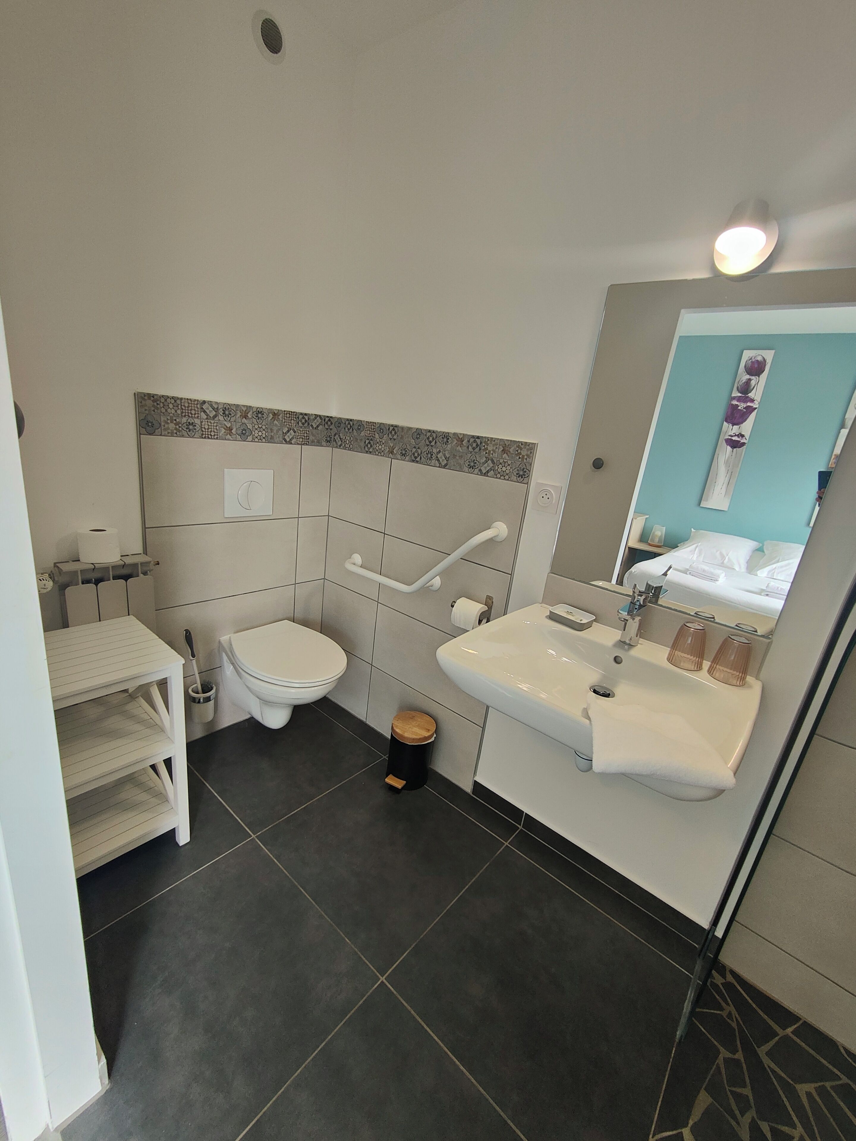 Une petite salle de bain comprenant des toilettes, un lavabo et une petite poubelle.