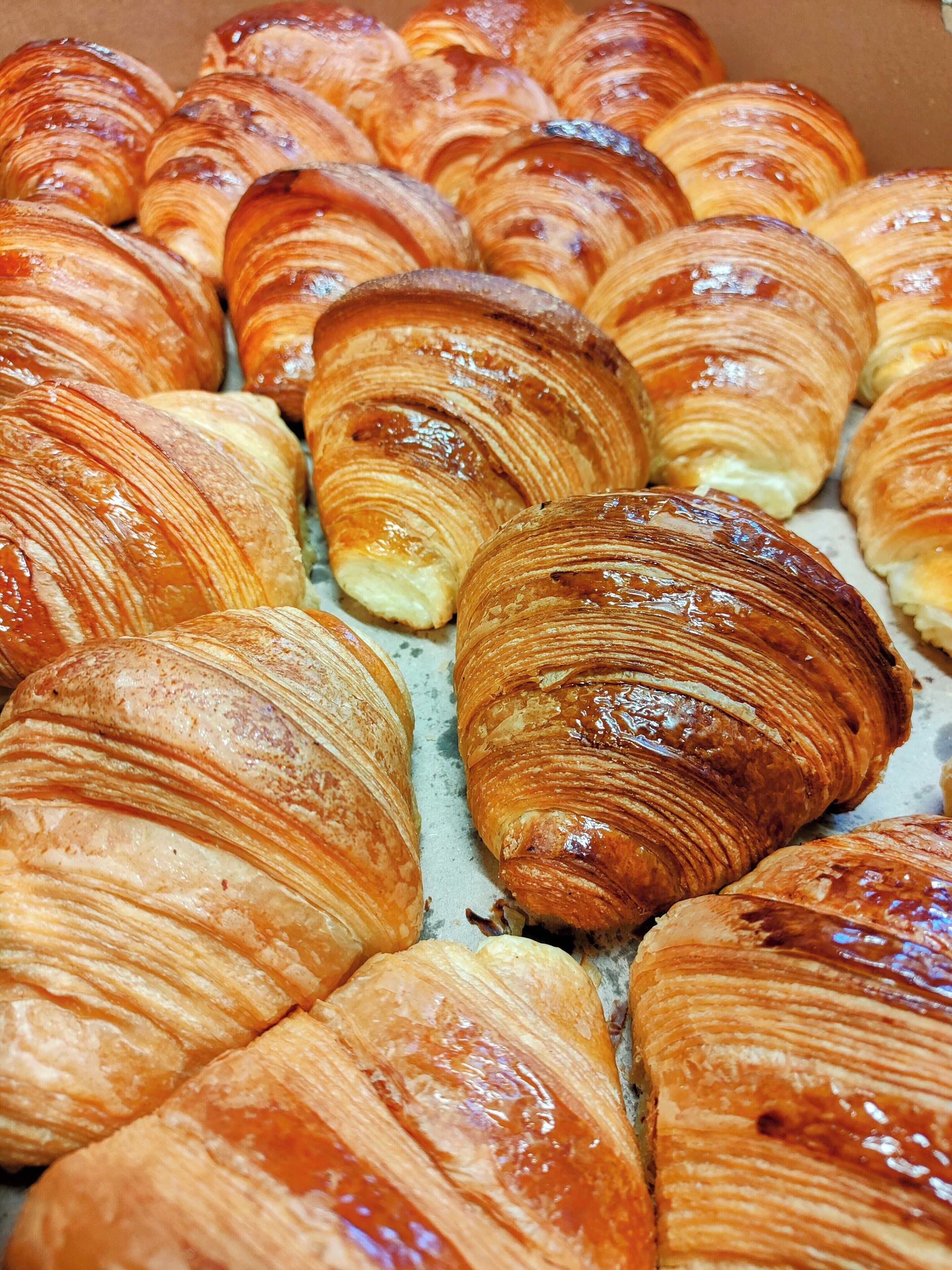 Uma caixa com diversos doces, incluindo croissants e outros produtos de pastelaria.