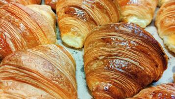 Uma caixa com diversos doces, incluindo croissants e outros produtos de pastelaria.