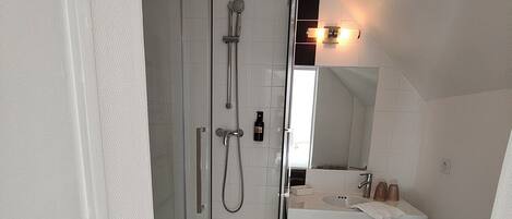 Un baño con cabina de ducha de vidrio, un lavamanos blanco y un inodoro.