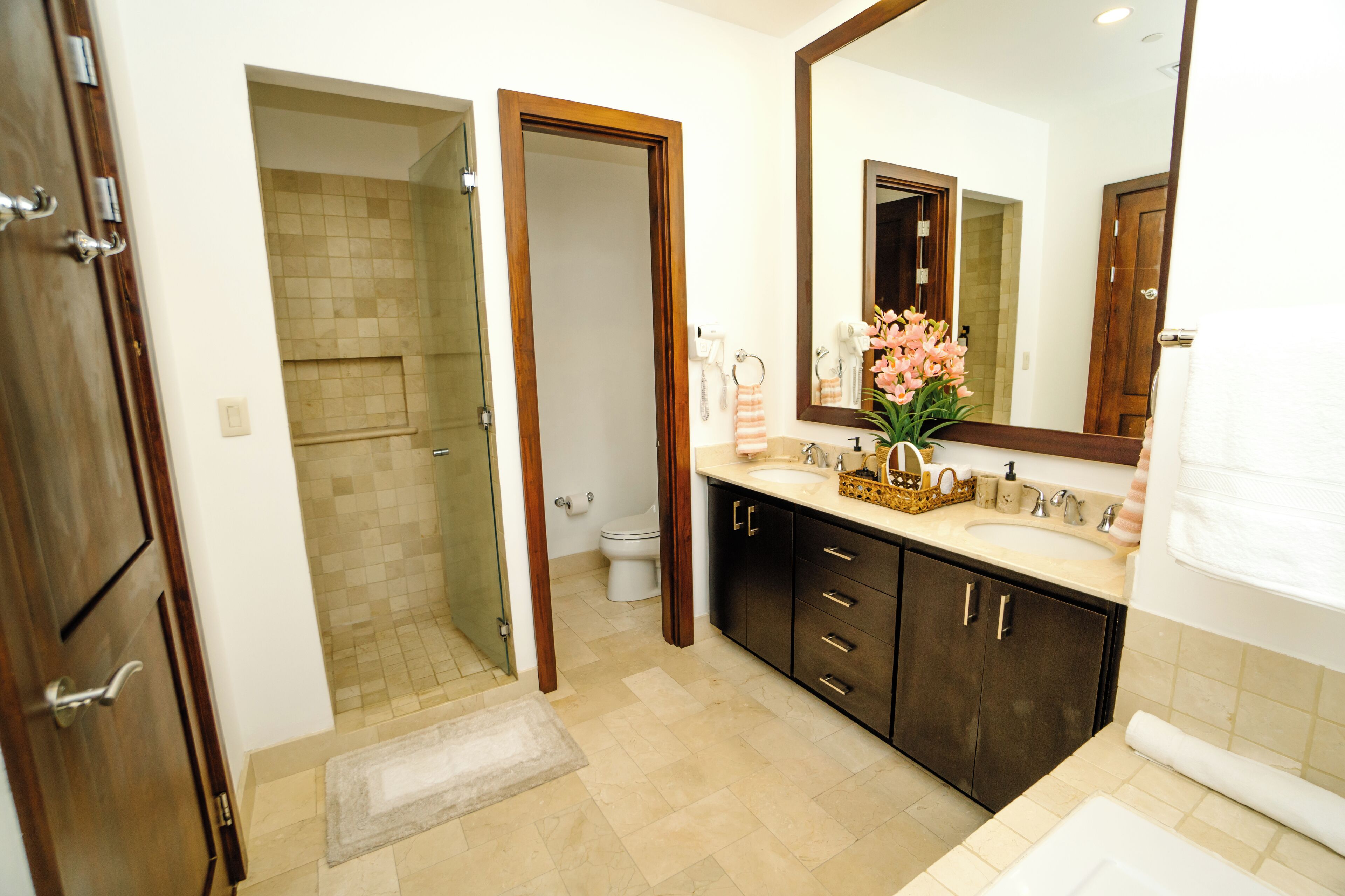 A bathroom with a large mirror, dark cabinets, a sink, and a shower area.