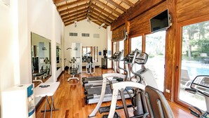 A gym with treadmills, exercise equipment, and a pool visible through the windows.