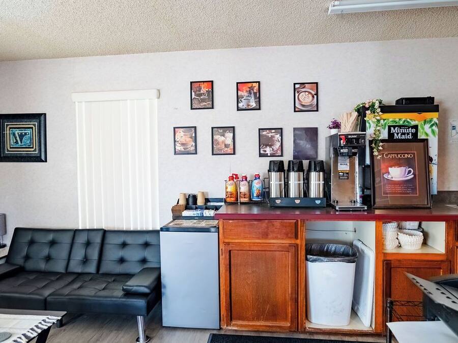 Un espai habitable compacte amb zona de cuina, un sofà de pell negra, nevera petita i cafetera.