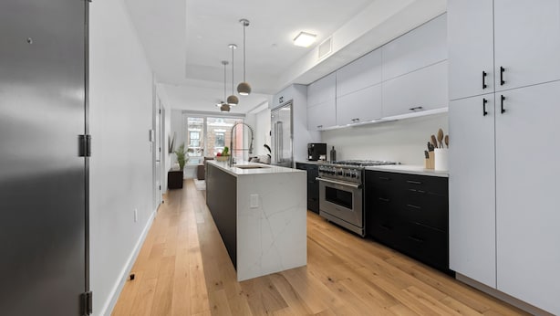Una cocina moderna con armarios blancos, una isla central y un horno de acero inoxidable.