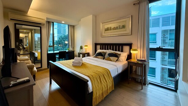 Habitación de hotel con una cama grande, un escritorio, una silla, un televisor y una ventana con vistas a la ciudad.