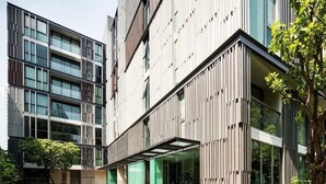 Un edificio moderno con patio interior, ventanas amplias y paneles de madera verticales.
