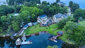 Vue aérienne d’une propriété située au bord de l’eau, avec une grande maison, un quai et des bateaux.